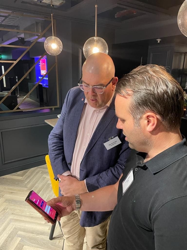 Two SALT team members reviewing the boat finance app on a phone at the company launch event